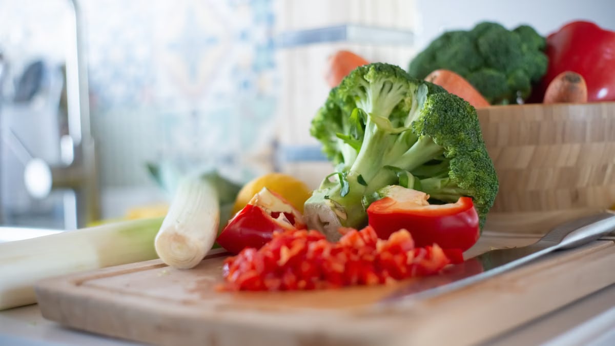 Colorful vegetables including broccoli and bell peppers on a chopping board, perfect for healthy cooking concepts.